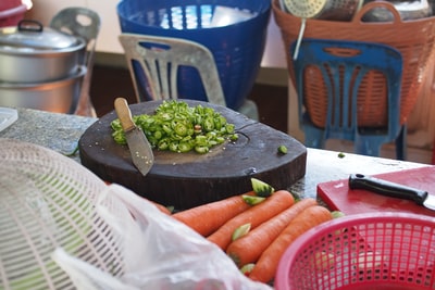 绿色蔬菜靠近米色菜刀都放在棕色的木板上